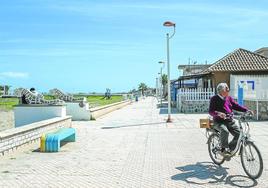 Un vecino en bicicleta por el paseo de Los Nietos, junto a la zona de fango del club naútico.