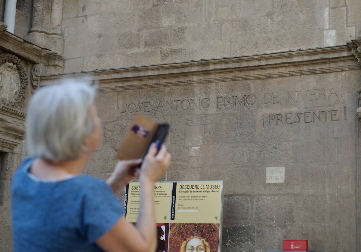 Una turista fotografía la Catedral de Murcia, junto al muro donde está la inscripción dedicada a José Antonio Primo de Rivera.