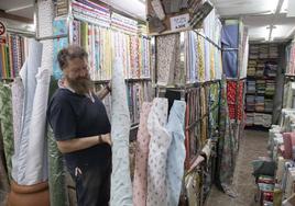 El vendedor Andrés García coloca unos rollos de tela en su popular tienda de Tejidos Santa Ana, que es un gran reclamo de las galerías comerciales del Cenit.