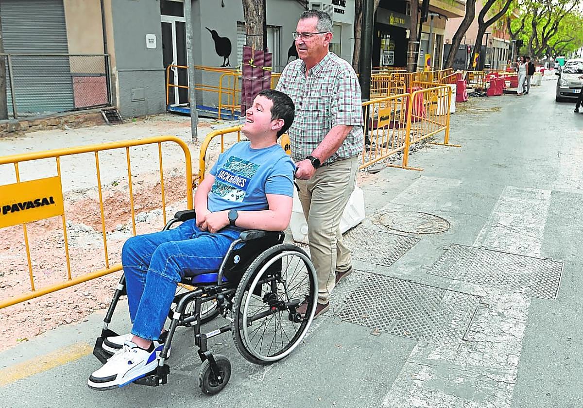 Fernando empuja la silla de ruedas de su hijo por una vía reservada a los coches en el barrio del Infante Juan Manuel.