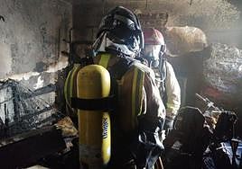 Dos bomberos en el interior de la vivienda afectada por el fuego.