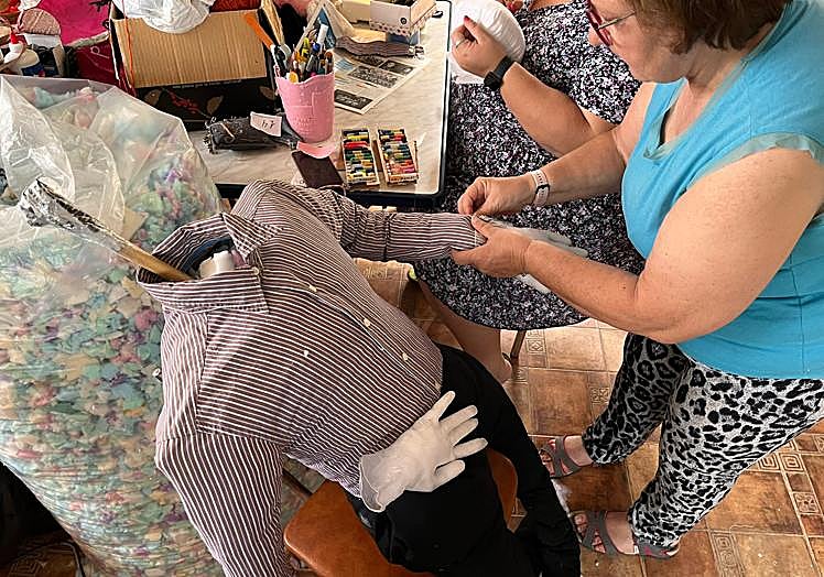 Una vez preparados los guantes, Egea los cose a la camisa para simular las manos. Al fondo, Serrano comienza a pintar la cara del mayo.