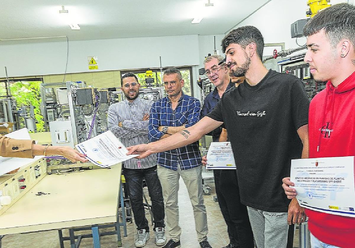 La directora del Servicios de Empleo y Formación (SEF) entrega los diplomas a tres alumnos que han participado en un curso sobre paradas de mantenimiento industrial.