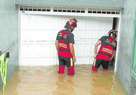 Dos bomberos acceden a una cochera inundada en Ciudad Jardín.