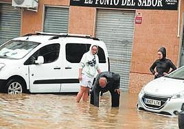 Vecinos buscan arquetas en una calle del barrio inundada el martes.