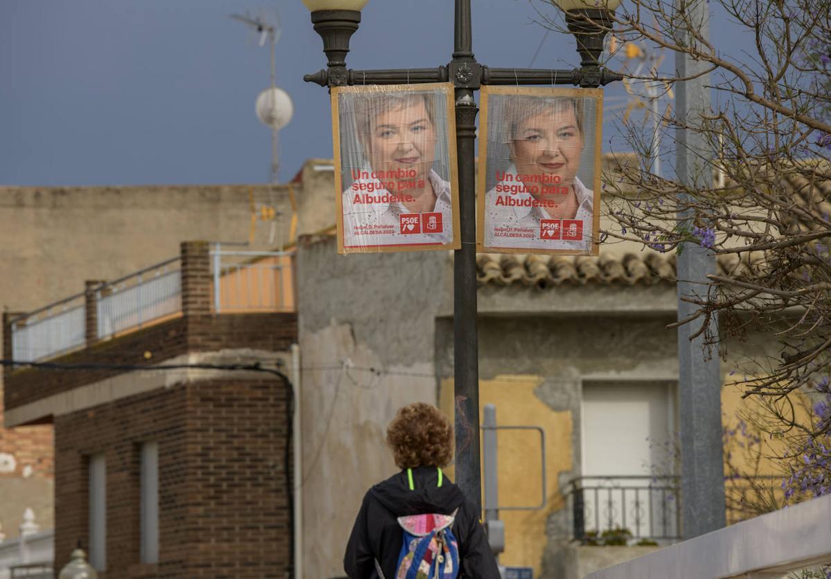 Una vecina de Albudeite pasa junto a los carteles de Isabel D. Peñalver, detenida por presunta compra de votos.