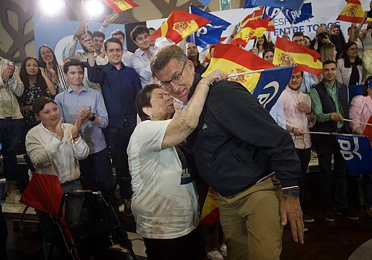 Los asistentes al mitin saludan a Feijóo.