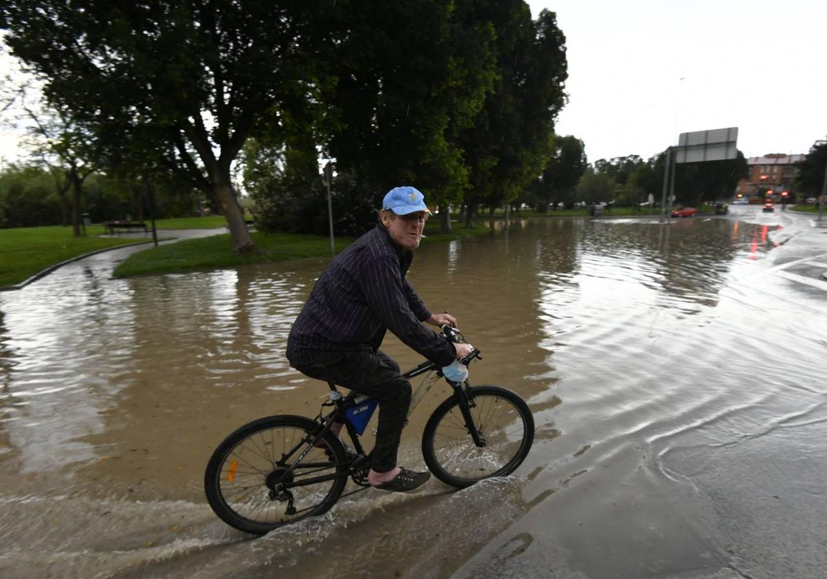 Un vecino de La Alberca recorre en bici una de las zonas inundadas, ayer, por las lluvias.