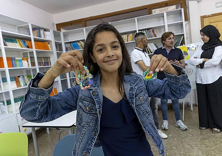 Omayma Bennouna sostiene sus pulseras mientras sus padres y el director del centro conversan detrás.