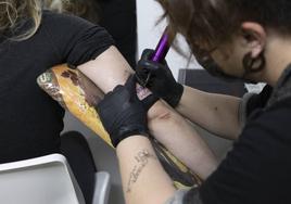 Una tatuadora realizando un tatuaje, en una imagen de archivo.