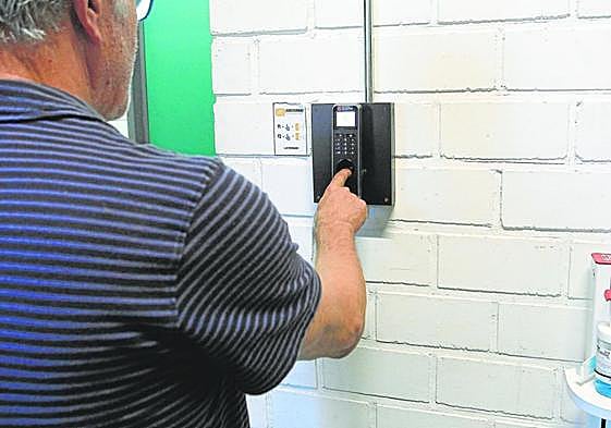 Un trabajador se identifica con su huella en un equipo de registro de horarios a su entrada a la empresa.