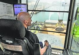 Un gruista, desde lo alto de la estructura, controla la pala que descarga cereal de un barco atracado en la terminal polivalente de Escombreras.