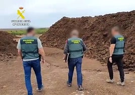 Tres guardias civiles, junto a dos montañas de estiércol, en una granja próxima al Mar Menor.