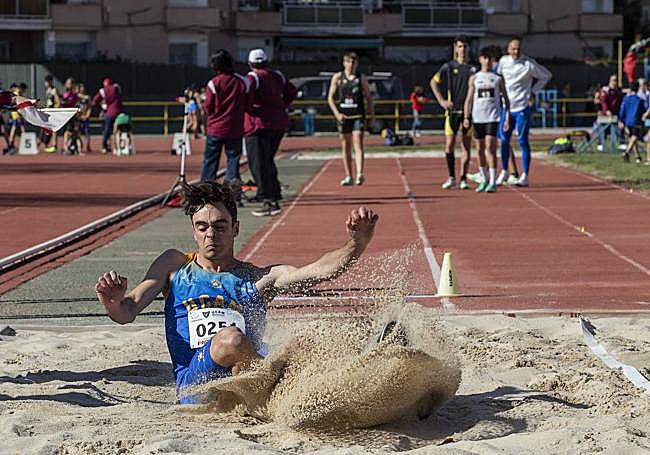 Un atleta cae al cajón de arena durante una de las pruebas de salto de longitud.