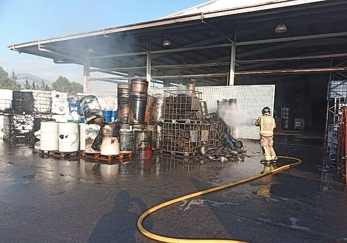 Un bombero apaga los botes y residuos quemados.