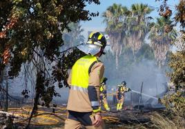 Efectivos de bomberos tratan de sofocar las llamas en el poblado chabolista junto a La Fica, en Murcia.