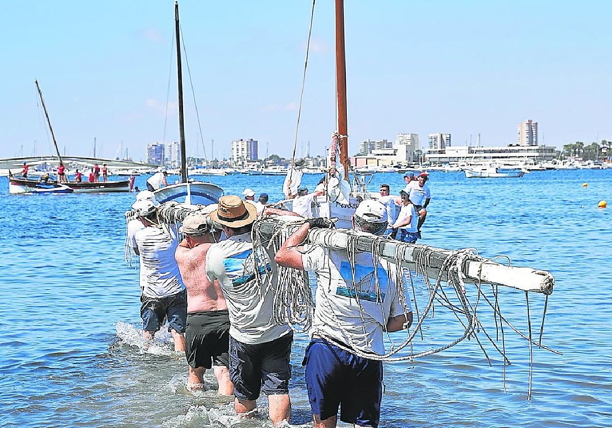 Regatistas se dirigen asu embarcacióncargando la botabara.