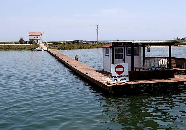Imagen principal - Muelle de acceso a la encañizada La Torre, solo para las embarcaciones privadas autorizadas; Julián Castejón y 'Sensi' sirven platos de caldero para los invitados; y una máquina draga el fango del fondo marino. 