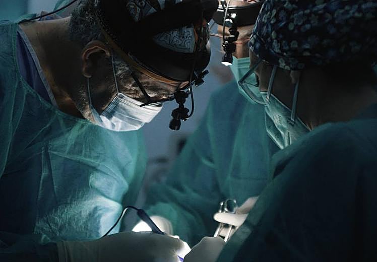 Imagen principal - Un equipo de la ONG realiza una intervención en el hospital keniano, mientras en la puerta colas de pacientes esperan para ser atendidos por los voluntarios. 