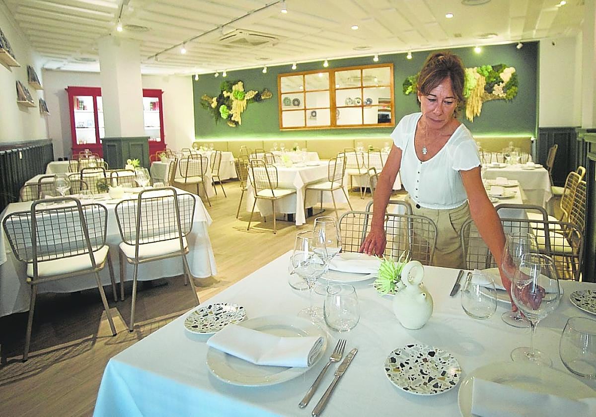 Una camarera prepara una mesa en la sala de un restaurante murciano.