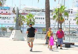 Un grupo de turistas andando por el muelle de cruceros Juan Sebastián Elcano, con el barco 'Wind Surf' al fondo.
