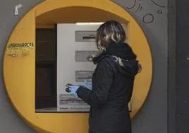 Una mujer saca dinero en un cajero, en una imagen de archivo.