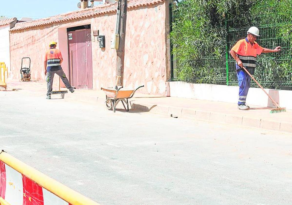 Dos operarios trabajan en las obras de pavimentación de una calle.