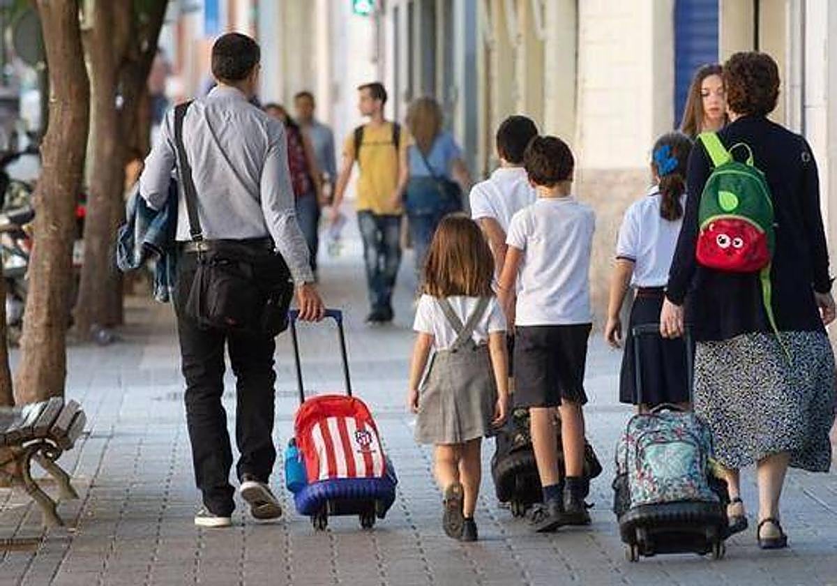 Imagen de archivo de unos padres llevando a sus hijos al colegio.
