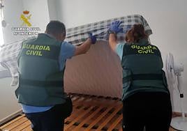 Dos agentes de la Guardia Civil inspeccionan uno de los domicilios en los que vivían las víctimas.