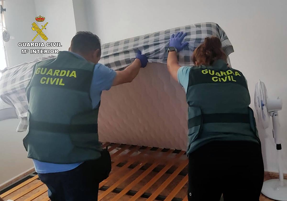 Dos agentes de la Guardia Civil inspeccionan uno de los domicilios en los que vivían las víctimas.