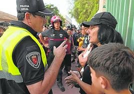Un policía local habla con una integrante de la protesta en el IES Antonio Menárguez (Los Alcázares), cerrado con una cadena.