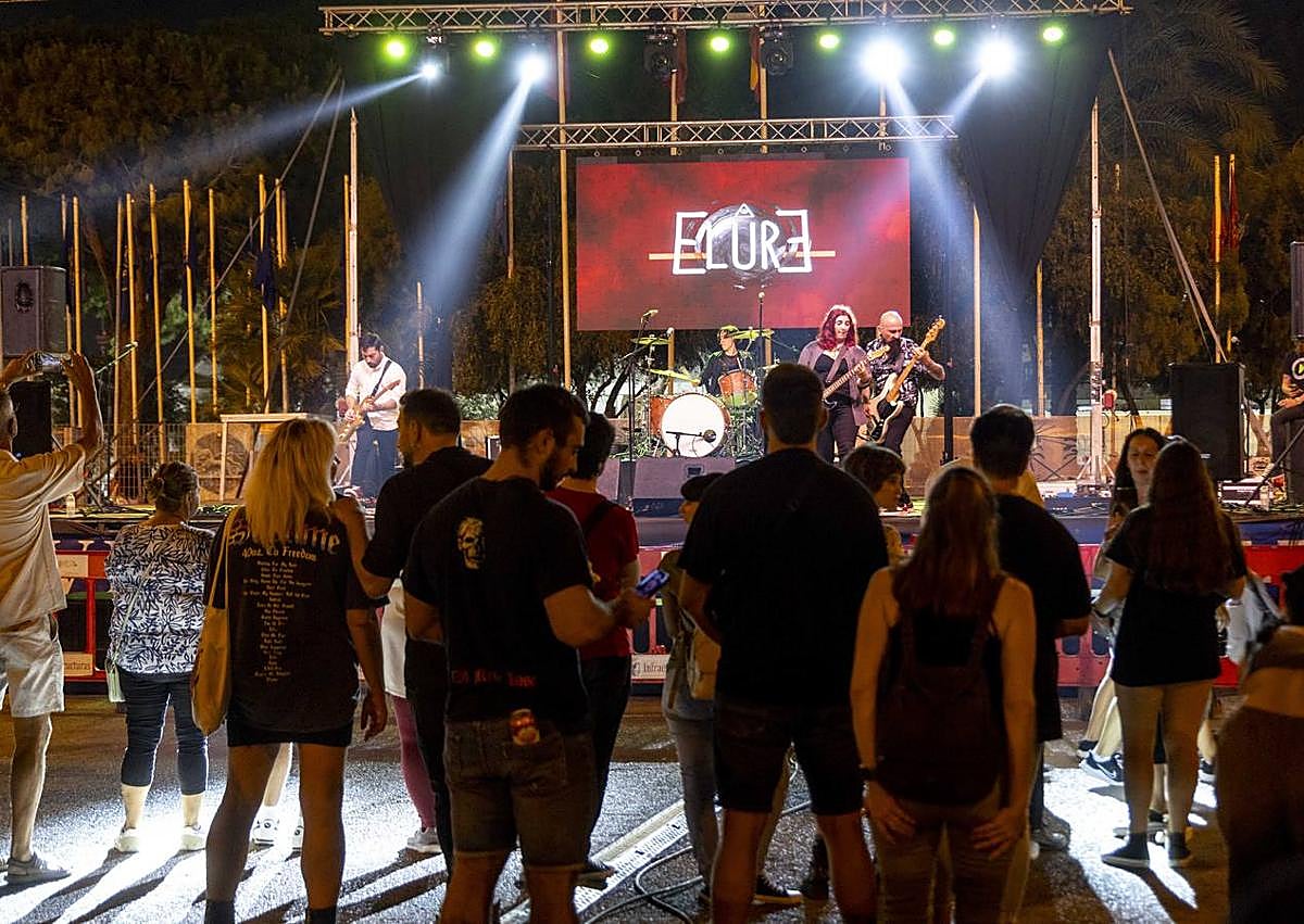 Imagen secundaria 1 - Uno de los momentos del acto de la Destrucción de Sagunto, celebrado en el escenario instalado en el puerto. |El grupo de música Elure, durante su actuación en el campamento festero, frente a su público. | Miembros del colectivo Saneamiento a Niños Afectados por Chernobyl (Sanac) preparan un caldero solidario.