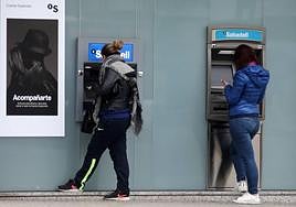 Dos mujeres consultan sus saldos antes de sacar dinero en cajeros, en una imagen de archivo.