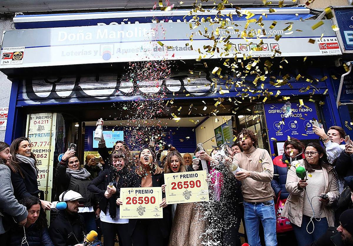 Un grupo de personas celebra frente a la administración de Dola Manolita que ha en el local se ha vendido un premio de El Gordo.