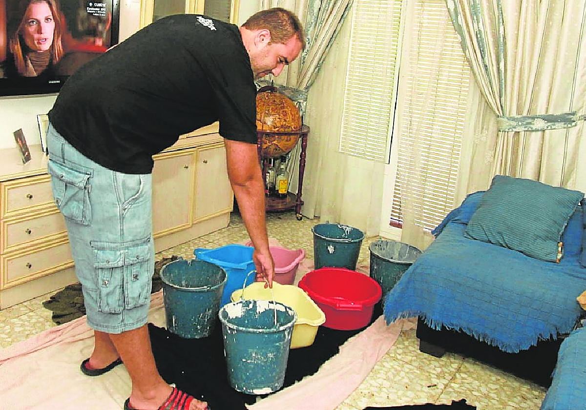 El propietario de una vivienda coloca baldes en su salón para el agua que cae desde goteras procedentes del piso de arriba.