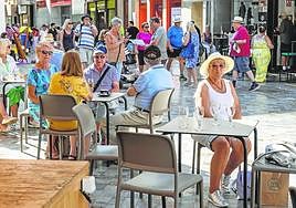 Turistas sentados en la terraza de un bar y otros paseando por la plaza San Sebastián.