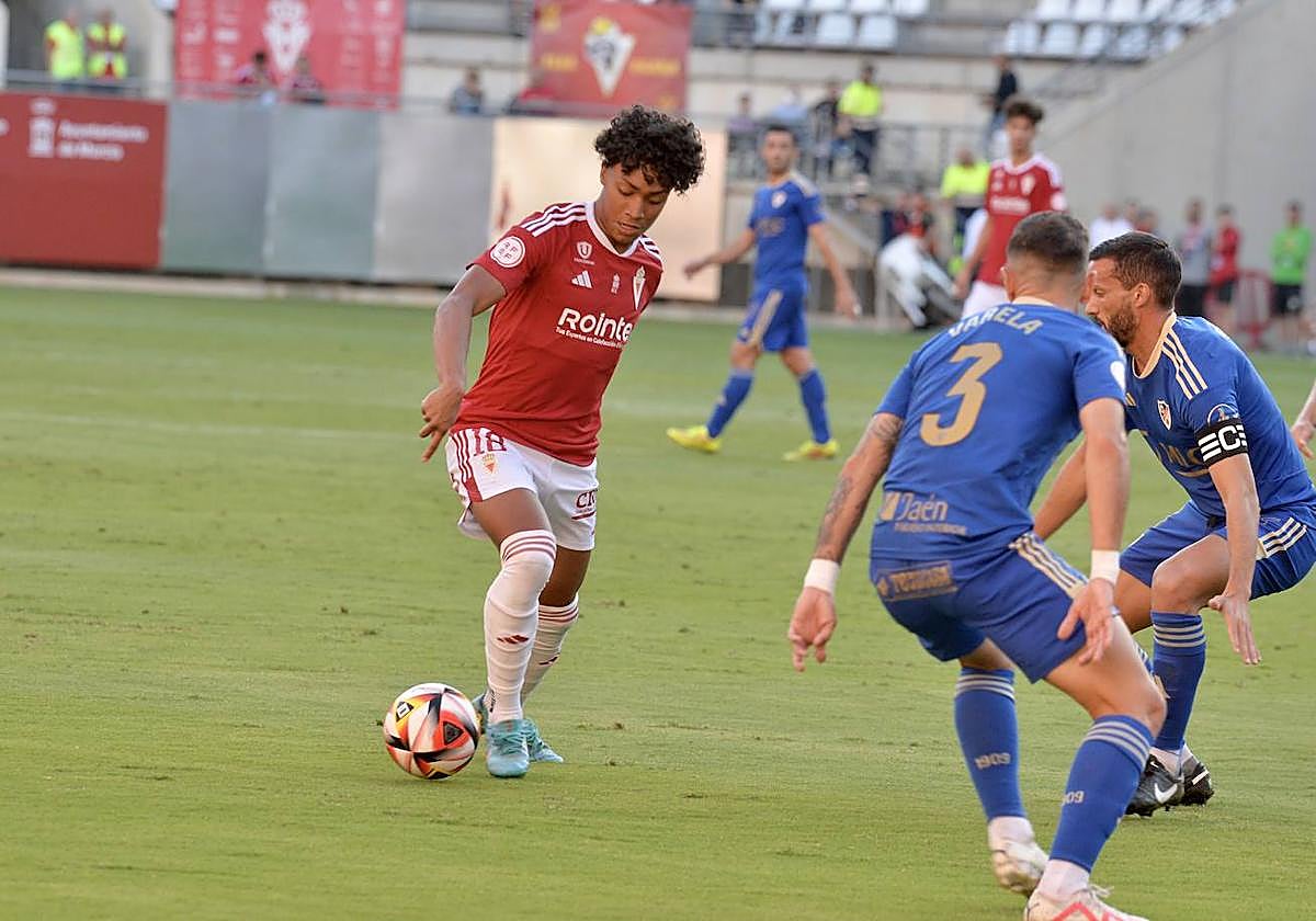 Carlos Rojas controla el balón ante dos adversarios.