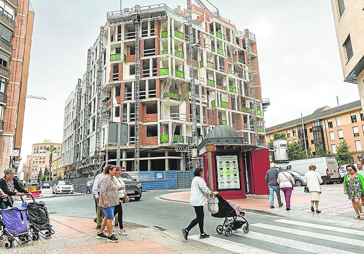Vecinos cruzando un paso de peatones y de fondo el inmueble que está terminando de construir el arquitecto Bernardino García, frente al mercado de Santa Florentina.