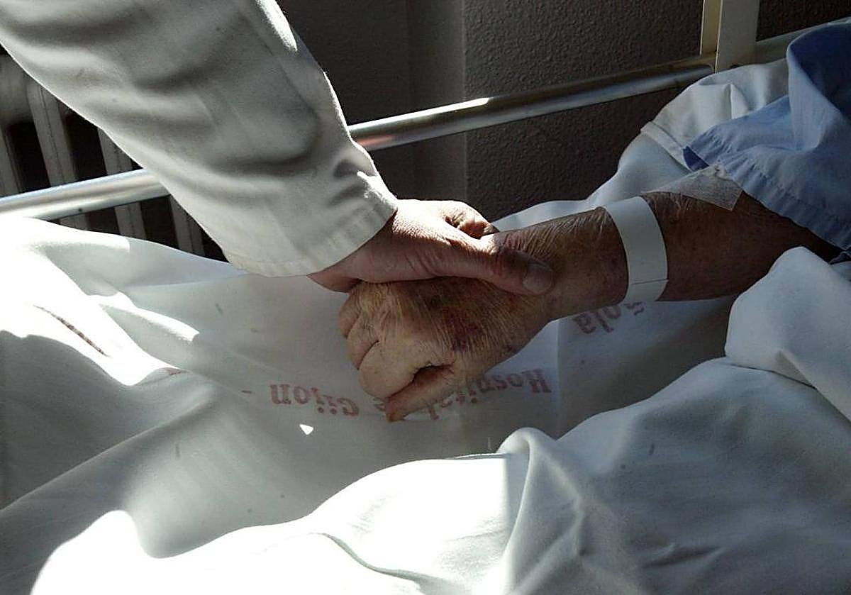 Un sanitario sostiene la mano de un paciente en una imagen de archivo.