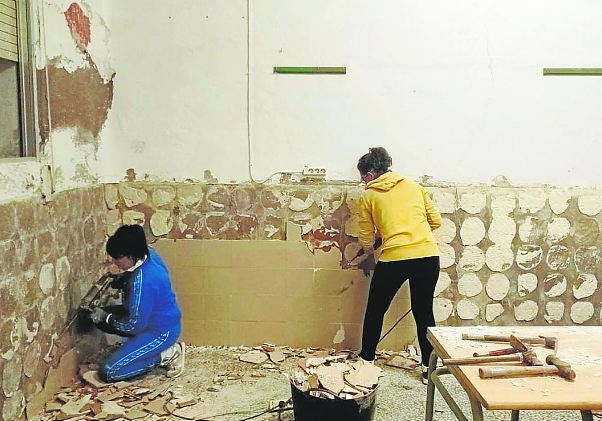 Dos mujeres realizan tareas de albañilería durante la preparación del comedor.