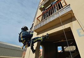 Un alumno de la academia de formación de bomberos desciende de la pared de un edficio en una simulación de un incendio.