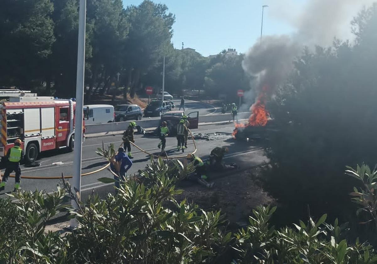 Los Bomberos apagan el incendio desatada en uno de los coches tras el accidente.