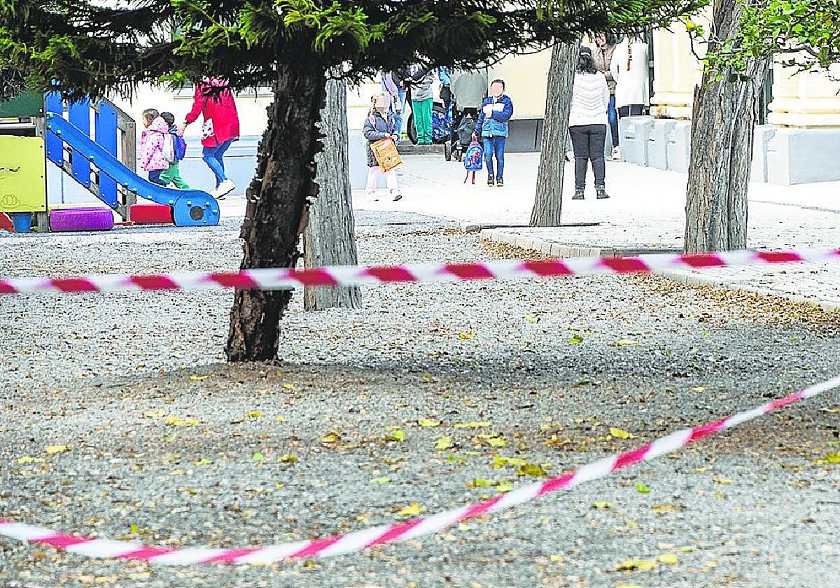 Precinto colocado en el acceso principal a la zona escolar de la Casa del Niño y al fondo, los alumnos a su entrada a clase.