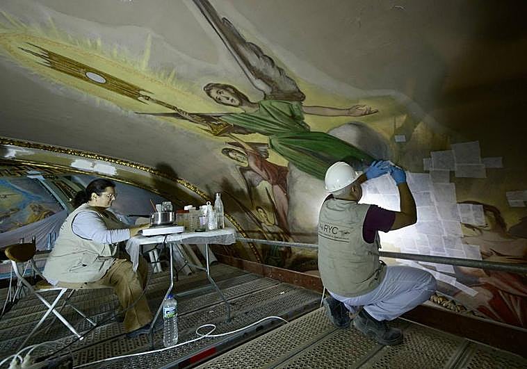 Isabel Sánchez y Javier Lérida, en la bóveda del presbiterio, trabajan en la escena que representa a un grupo de ángeles con la custodia.