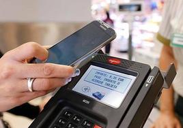 Una cliente paga con su móvil una compra.