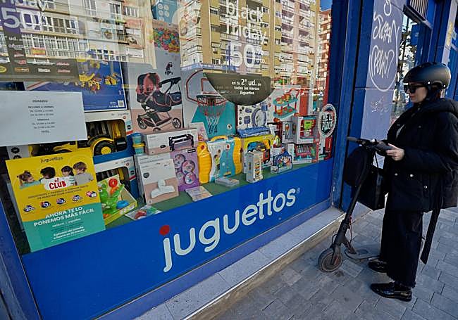 Una clienta revisa el escaparate de Jugettos en Murcia en busca de regalos.