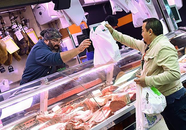 Pedro Cerezo, vicepresidente del Mercado de Verónicas de Murcia, sirve un pedido a un cliente en su carnicería.