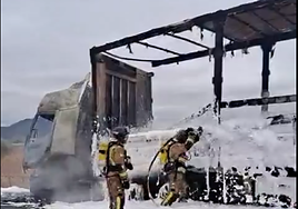 Dos bomberos apagan el fuego de un camión.