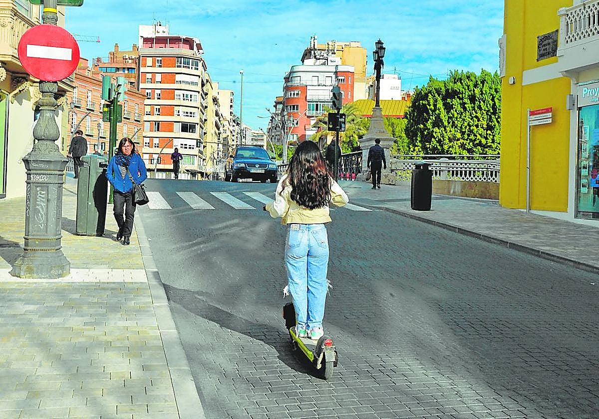 Una usuaria del patinete se acerca al Puente de los Peligros en dirección contraria.