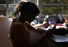 Imagen de archivo de un estudiante usando el móvil en clase.